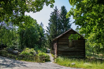 Fototapeta na wymiar Small wooden cottage in lush green countryside on a sunny day in Sweden