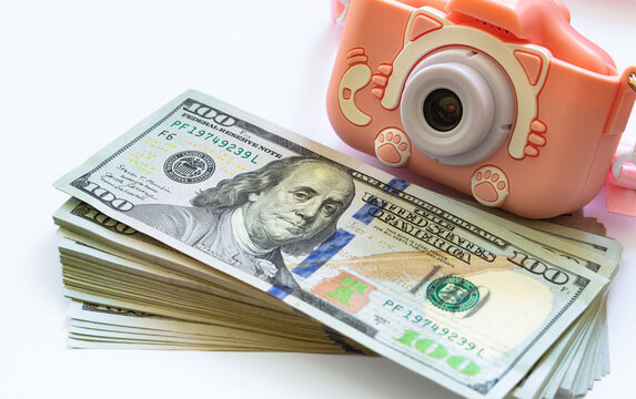 US 100 dollar banknotes and toy photo camera - Powered by Adobe