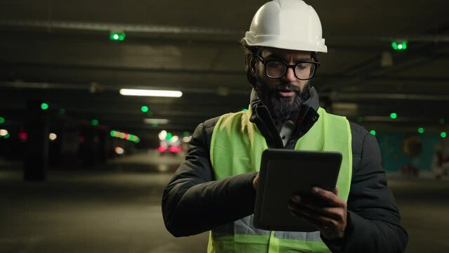 Heavy industry technology engineer Arabian man Indian builder in hard hat electrician architect manufacture worker think pensive ponder problem solution use digital tablet check cyber security system