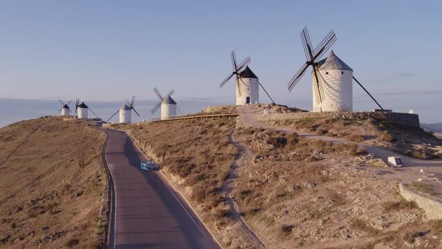 Men is running in front of Molinos de Viento de Consuegra golden sunrise, aerial 4k