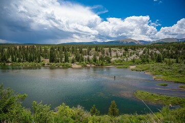 Fototapeta premium View of a lake and a green landscape under the blue sky with clouds in Colorado