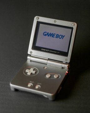Vertical shot of a vintage gray Game Boy Advance SP on a dark surface