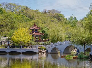 White bridge over a lake between green trees at Chang Lai Yuan Gardens