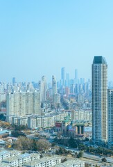 Vertical shot of cityscape with urban towers and skyscrapers over houses under blue sky