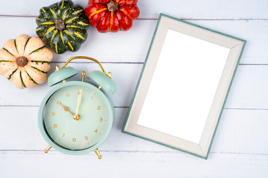 The Top view of blank photo frame and vintage alarm clock with pumpkin on wooden background, Save clipping path.