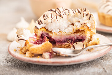 Two tartlets with meringue cream and cup of coffee on brown concrete, side view, selective focus.