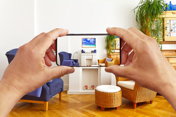 Augmented reality concept: hands holding smart phone with AR interior decoration app, visualising the living room with additional photo frame.