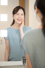 Obraz premium 洗面台や鏡台で美容を気にする女性 鏡などで確認する