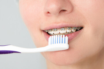 Close-up of a woman with braces brushing her teeth. Orthodontics and dental care. Photo