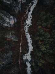 Obraz na płótnie Canvas Drone top down shot of a river in a mountain between rocks and trees moody winter Greece