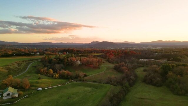 Rotating drone over countryside green meadows in Roanoke, Virginia with sunset sky on the horizon
