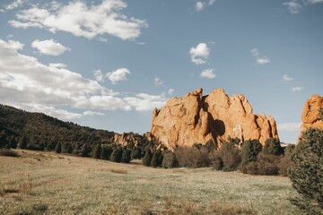 Scenic view of a huge rock formation in the woods surrounded by trees in sunlight