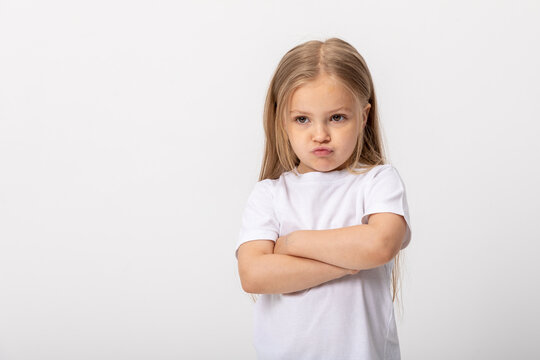 Negative human emotions, reactions and feelings. Isolated shot of moody displeased angry little girl crossing arms on her chest, pouting lips, having offended facial expression, being capricious