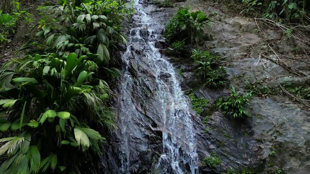 Drone shot of a small jungle waterfall surrounded by plants and rocks, without people in the touristic village of Minca, close to Santa Marta in Colombia.