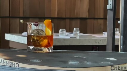 Close-up view: Rich golden whiskey in glass gets orange peel twist