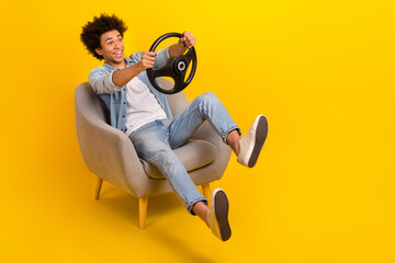 Full size photo of overjoyed carefree person sit chair hands hold wheel empty space isolated on...