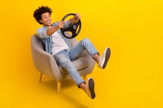 Full Size Photo Of Overjoyed Carefree Person Sit Chair Hands Hold Wheel Empty Space Isolated On Yellow Color Background