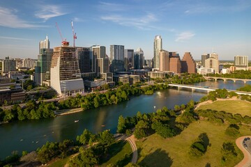Fototapeta na wymiar Drone shot of TX skyline with waterfront, greenery and blue cloudy sky in Austin city