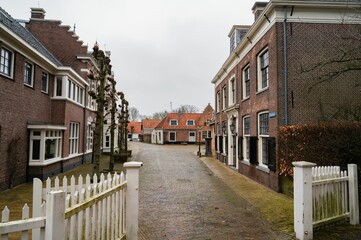 Group of brick traditional buildings behind a white fence