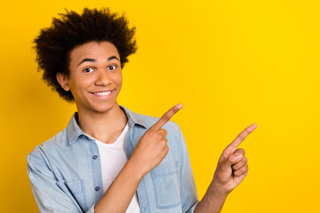Photo of beaming funky guy dressed denim shirt showing two fingers empty space isolated yellow color background