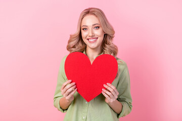 Photo of adorable shiny woman dressed green shirt holding large big heart isolated pink color background