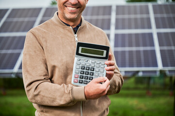 Smiling man showing future income from investing in alternative energy. Cropped picture of happy...