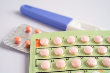 Pregnancy test and birth control pills on calendar, contraception health and medicine.