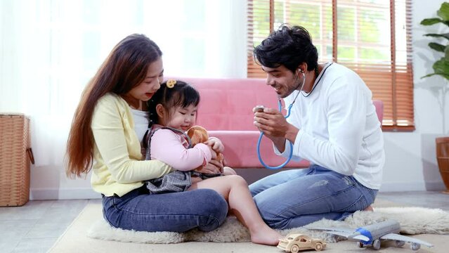 Dad plays doctor using stethoscope check cute daughter, happy family, family activities on vacation