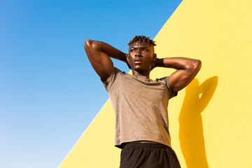 Young man doing stretching exercise outside. African man training outside.