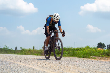 Asian male cyclist riding bicycle on gravel road