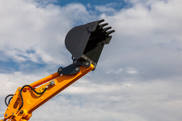 Excavator boom with open bucket against blue sky