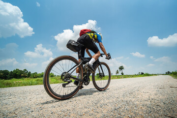 Asian man riding bicycle on gravel road at high speed