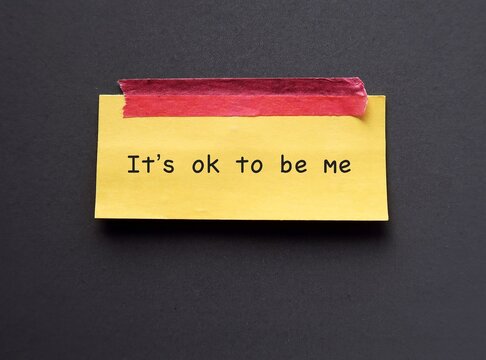 Yellow note stick on blue background with text 'It’s ok to be me' concept of using positive sentences mantra affirmation will immediately change the way we think and boost self esteem