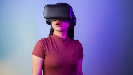 Surprised young Asian Indian woman wearing a virtual reality headset, a shocked girl with vr glasses concept studio portrait
