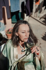 Elegant adult woman drinking white wine outdoors