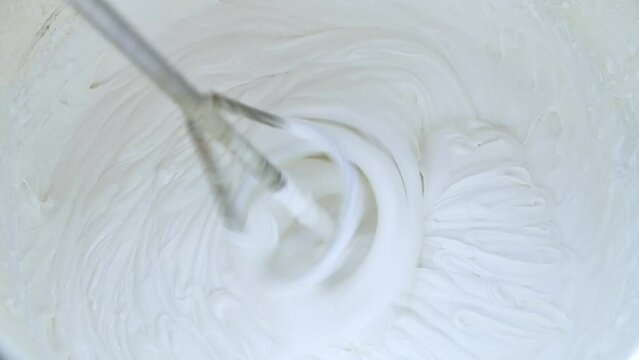 Mixing white putty in a bucket. The worker mixes the mixture with a mixer. Closeup.