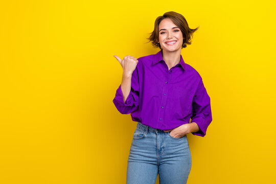 Portrait of attractive lady banker direct finger empty space wear violet blouse jeans pants isolated yellow vivid color background