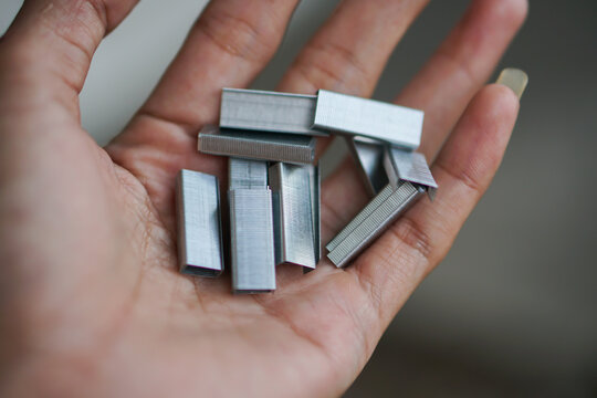 Hand holding a stack of metal staple for stapler 