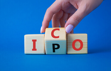 ICO and IPO symbol. Businessman hand turns wooden cubes with words ICO - initial coin offering and...