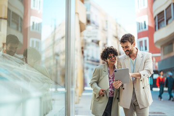 Chasing after success with the best connection. Shot of two businesspeople using a digital tablet in the city. Business colleagues are using digital tablet outside the company building.