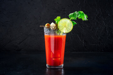 Bloody Mary cocktail with garnish on a black background. Spicy tomato juice with alcohol, lime,...