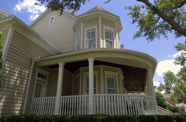 Wrap-around wooden veranda on a Queen Anne style house on a beautiful summer day