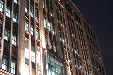 Exterior façade of a concrete building with windows and a glass entrance at night in Montreal