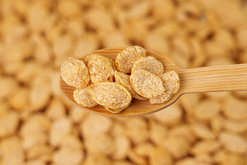 Dry crispy quinoa flakes in the form of seeds in a bamboo spoon