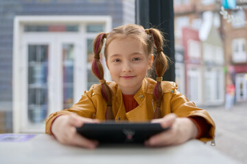 Portrait of a beautiful white girl with ponytails playing video game on a smart phone. Friendly...
