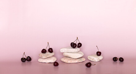 Empty podium or pedestal made of natural pebbles and fresh cherries on pink background. It can be...
