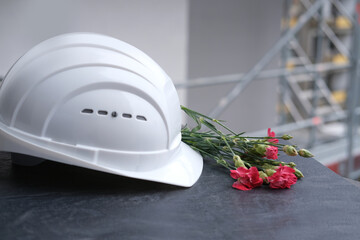 white hardhat, red carnations, helmet on background of buildings, protection inspecting at...