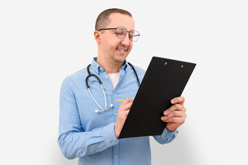 Male doctor making notes on a clipboard on a gray studio background. Health care and medicine