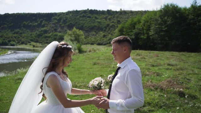 Young couple in love bride and groom, wedding day near a river. Steadycam shoot