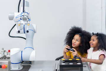 Kid female teen child enjoy Machine Learning Robot arm is Moving Under Control robot at technology class, stem education robot arms for digital automation software for artificial intelligence ai © BESTIMAGE